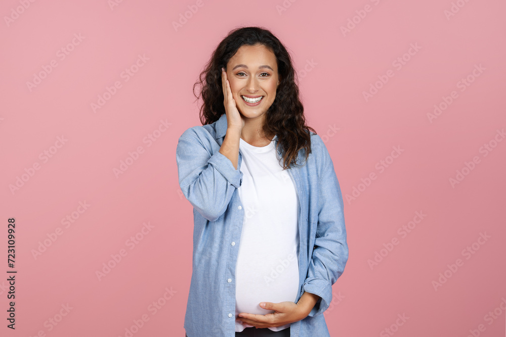 Fototapeta premium Happy pregnant woman touching her face and belly