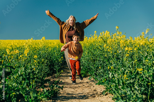 Playful mother and son running in rapeseed field