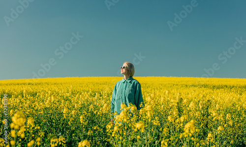 Woman standing amidst flowers in rapeseed field
