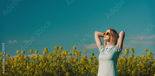 Woman with hands behind head standing in field at sunny day photo