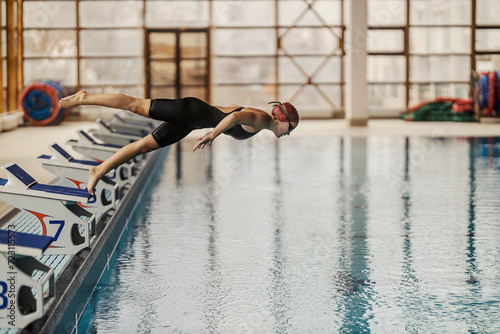 A young female swimmer is diving and jumping into the swimming pool on her training. © dusanpetkovic1