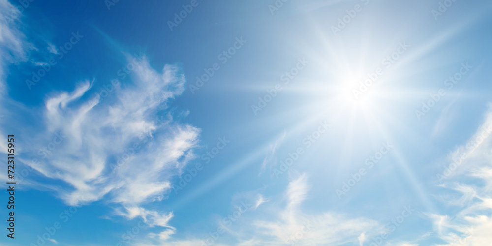 There are light white clouds and bright sun in the blue sky. Wide photo. There are light white clouds and bright sun in the blue sky. Wide photo.