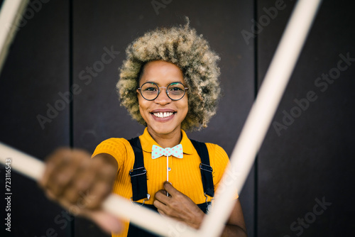 Smiling woman holding prop in front of black wall photo