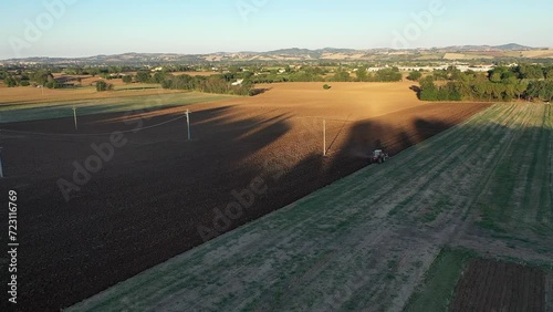 Trattore agricolo che ara un campo prima della semina del grano in Italia. Video in 4K photo
