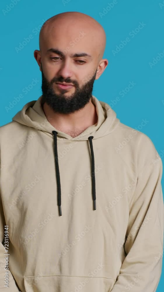 Vertical Video Arab person showing negative sign with fingers, expressing his refusal in front of camera. Middle eastern guy does no symbol in studio, presenting rejection and restriction gesture