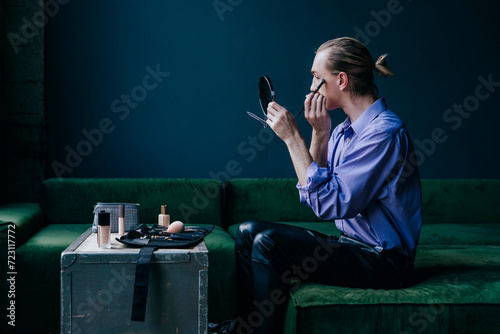 Make-up artist applying eyeshadow looking in hand mirror photo