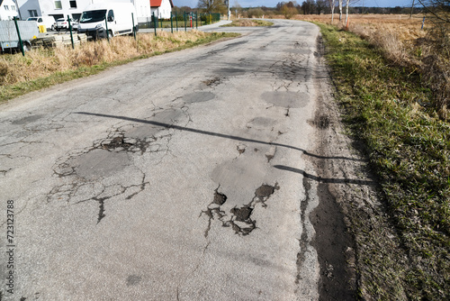 A damaged and hole-punched aflat road in the countryside. photo