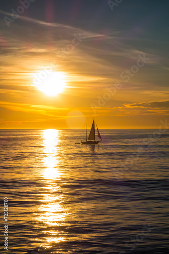 Sailboat sailing while the sun sets behind tteh pacific ocean in Venice Beach, california.