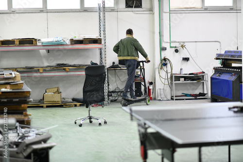 engineer in an electronic repair shop workshop rides electric scooter in a factory