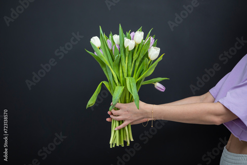 Young woman holding a bouquet of flower isolated on black background