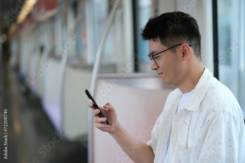 Photography Asian young man using smartphone inside subway
