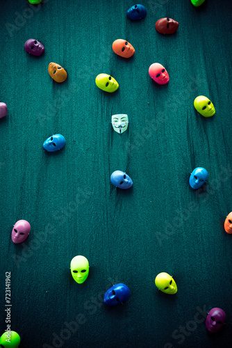 Different colorful carnival masks scattered on a green background.