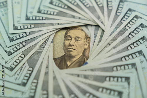 A Japanese 10000 yen banknote surrounded by US dollars banknotes photo