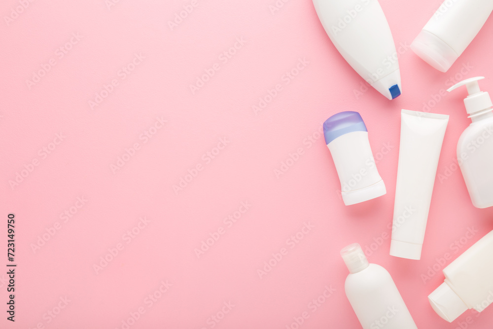 Different white plastic cosmetic bottles on light pink table background. Pastel color. Care about clean and soft body skin. Daily beauty products. Closeup. Empty place for text. Top down view. - obrazy, fototapety, plakaty 