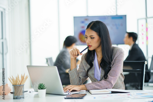 Happy young confident businesswoman sitting at the office table with group of colleagues