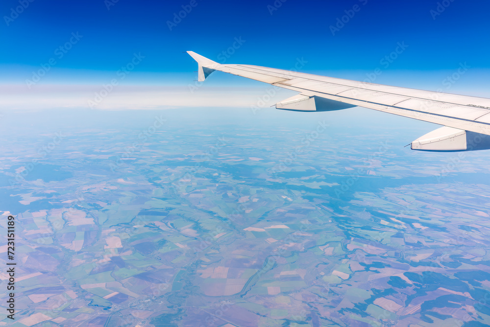 Aerial view from airplane window above green ground. View from the airplane window with beautiful clouds at sunrise Aerial view from airplane window above green ground. View from the airplane window with beautiful clouds at sunrise