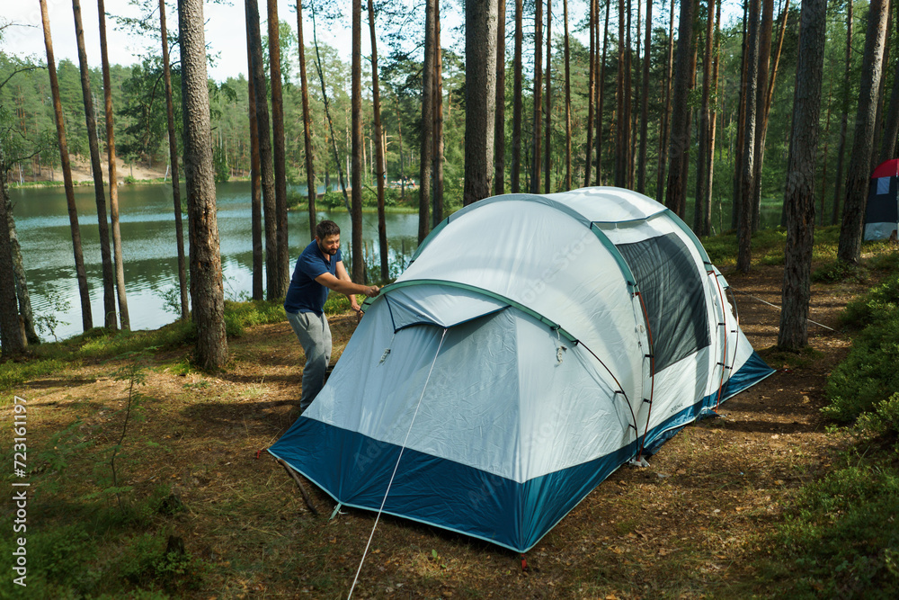 caucasian man putting up a tent in pine forest. Family camping concept