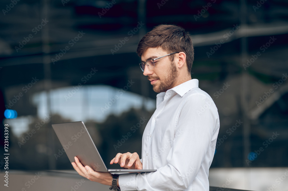 Young male manager with a laptop looking contented Young male manager with a laptop looking contented