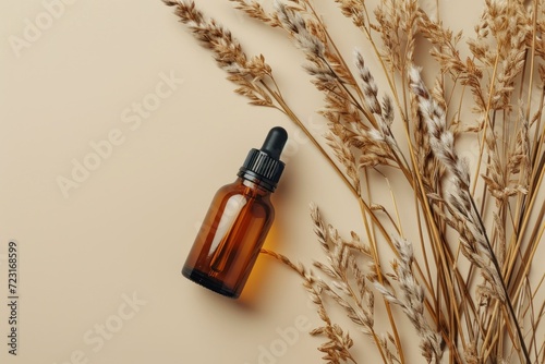 Amber glass bottle with pipette on beige background adorned with dry wild reeds representing natural cosmetics for skin care