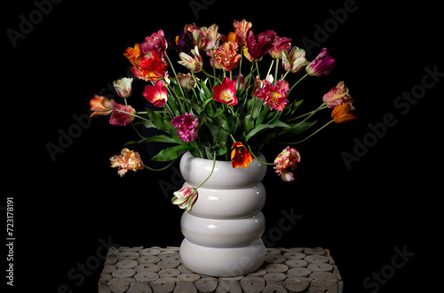flower arrangement with colored silk flowers in vase. Black background. Studio photo.