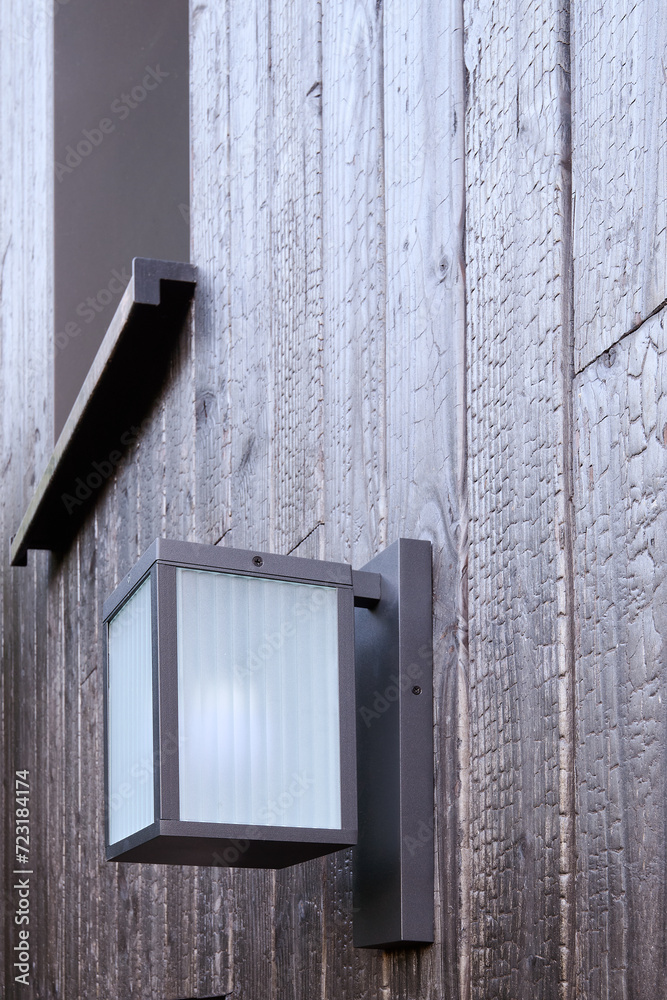 Modern external lamp on burned wood wall