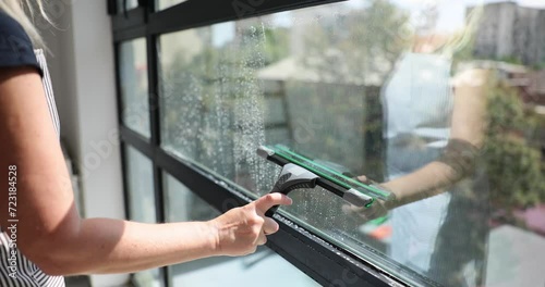 Closeup of hands cleaning windows with squeegee photo
