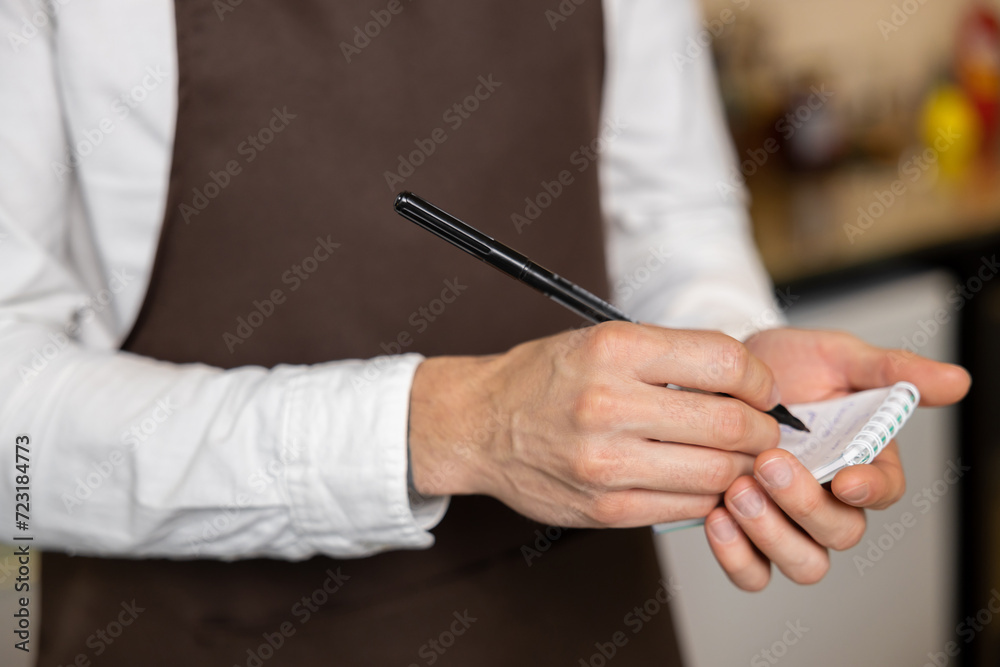 Waiter in pizzeria making notes and smiling