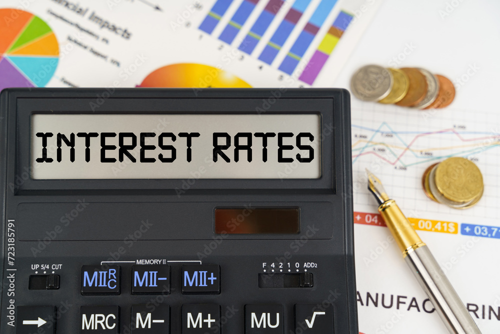 On the table are financial reports, coins and a calculator with the inscription - Interest rates On the table are financial reports, coins and a calculator with the inscription - Interest rates