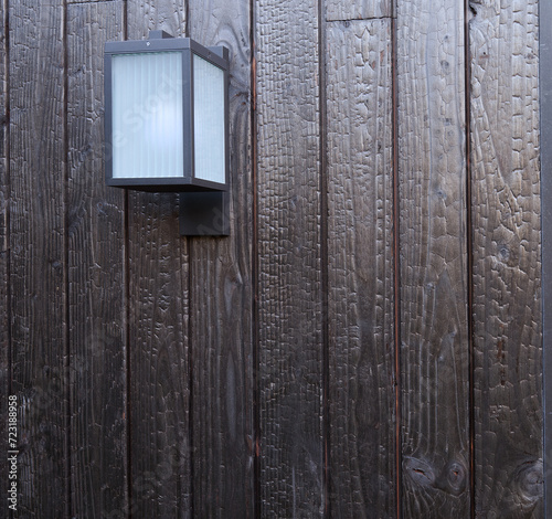 Modern external lamp on burned wood wall