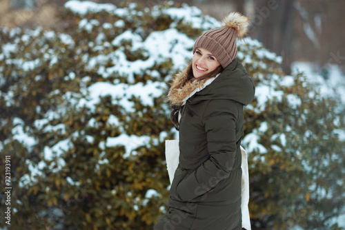 smiling modern woman outdoors in city park in winter