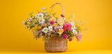 an arrangement of flowers in a basket on a yellow bac