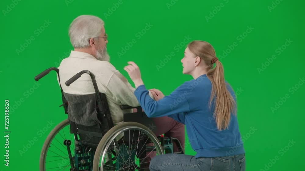 Portrait of aged disabled man on chroma key green screen. Senior man in wheelchair talking with girl assistant or granddaughter. Portrait of aged disabled man on chroma key green screen. Senior man in wheelchair talking with girl assistant or granddaughter.