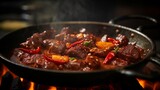 Close-up of sizzling, spicy stewed beef in a hot pan.