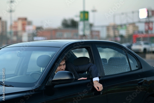 man arrived at the parking lot and climbs out of the car through the window © Вячеслав Думчев