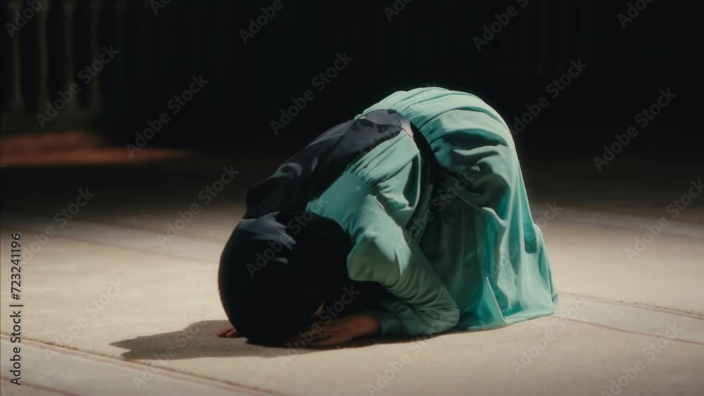 Young Muslim Woman Prostrating in Prayer in a Mosque at Night. The Act of Sujud Young Muslim Woman Prostrating in Prayer in a Mosque at Night. The Act of Sujud