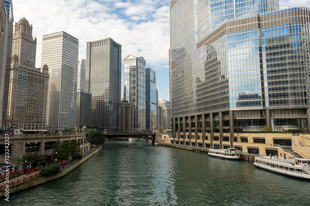 Fototapeta premium Riverwalk passes between the tall buildings in the city. Towers and water.