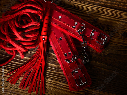 BDSM sex toys set in a red color over aged wooden planks backdrop