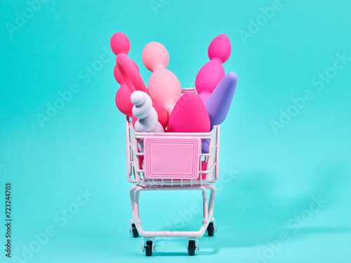 Female pink sex toys in shopping trolley over turquoise background