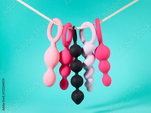 Set of sex toys hanging on a rope over blue turquoise background