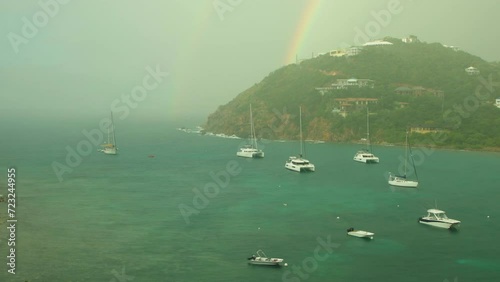 Boats anchored in cozy harbor during rain shower and rainbow