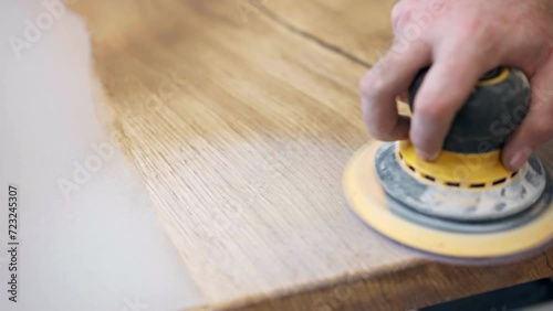 Trendy tabletop made of wooden slabs and white pearl colour epoxy resin, carpenter polishing tabletop with grinder machine to make it smooth and brilliant, work with wood and epoxy resin in workshop