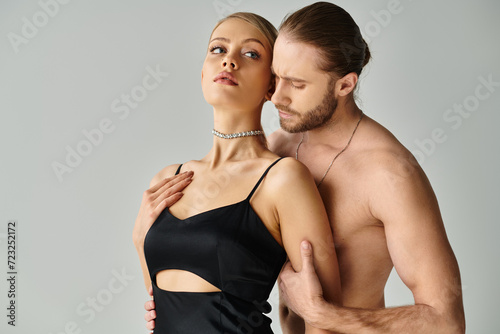 good looking shirtless man with beard hugging his beautiful young girlfriend alluringly, sexy couple