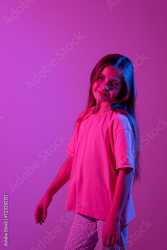 Portrait of cute smiling girl on pink background with blue neon light. Party concept. Different emotions. Happiness, childhood, holidays, women's day, lifestyle. Copy space. 