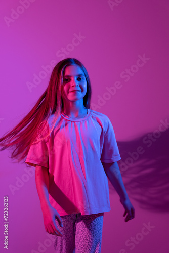 Portrait of cute smiling girl on pink background with blue neon light. Party concept. Different emotions. Happiness, childhood, holidays, women's day, lifestyle. Copy space. 
