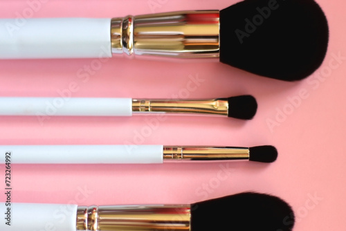 Various different make up brushes on pink background. Selective focus.