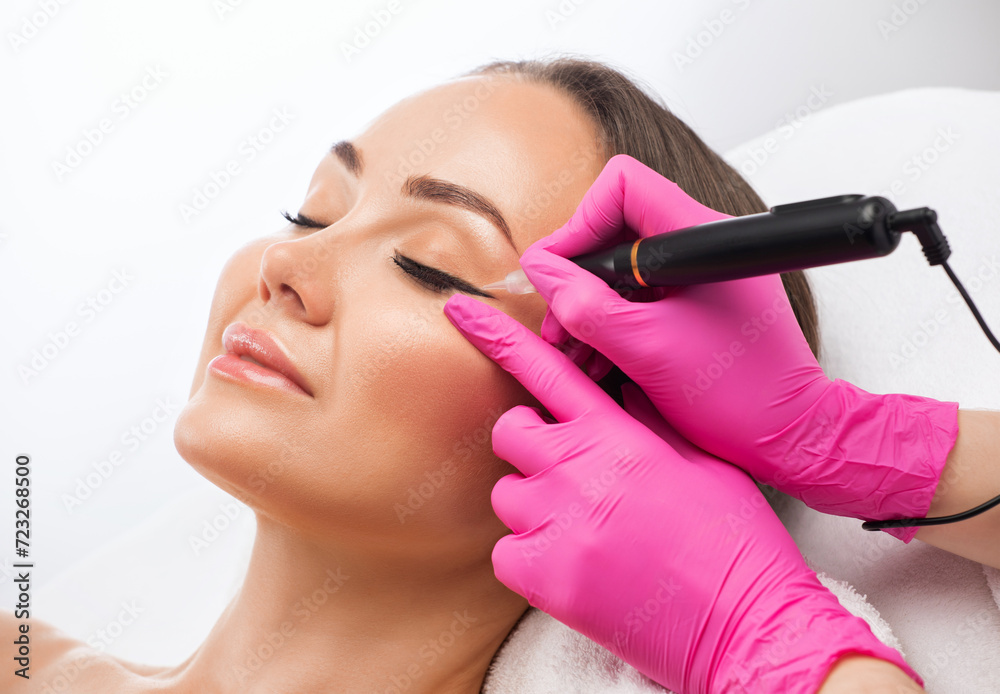 Permanent make-up for eyebrows of beautiful woman in beauty salon. Closeup beautician doing eyebrows tattooing. arrows on the eyes