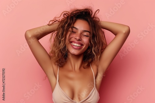 A beautiful young smiling girl on a coloured background has her hands up in the air and is laughing