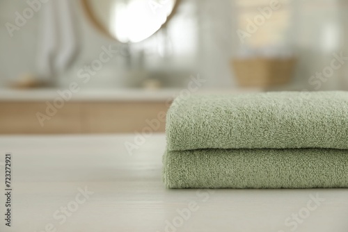 Stack of clean towels on white wooden table in bathroom. Space for text