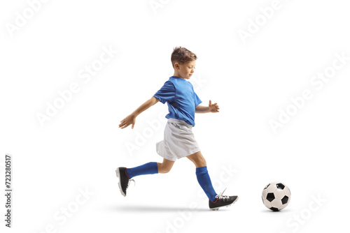 Boy in a blue and white football kit running fast with and leading a ball