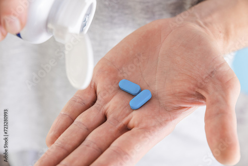 Man pouring PrEP blue pill from medical bottle in a hand. HIV prevention using Pre-Exposure Prophylaxis medicine. Men health. AIDS prevention concept